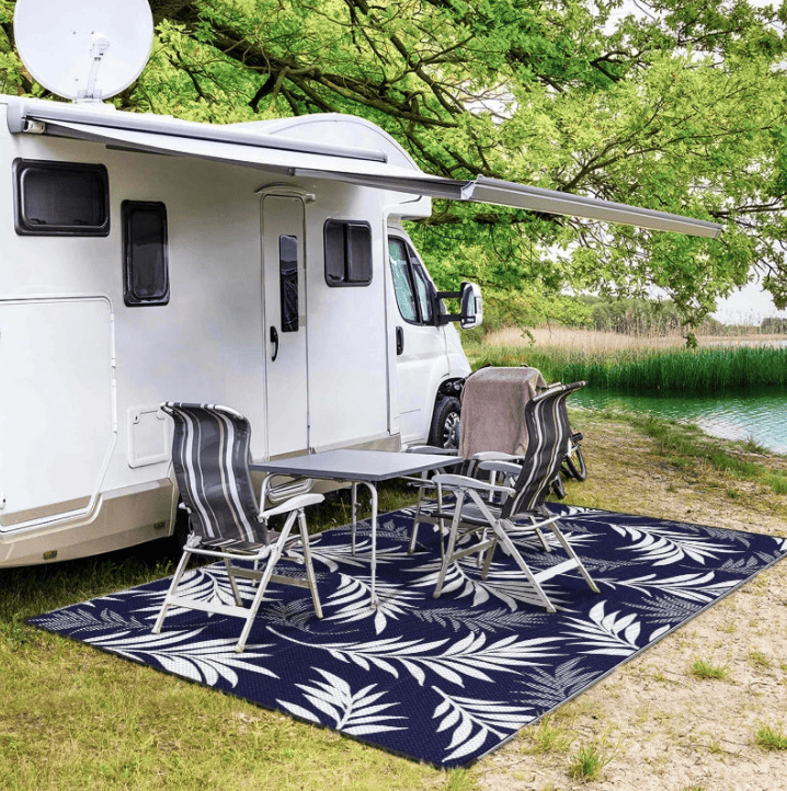 Tapis extérieur jardin avec motif de feuilles blanches sur fond bleu, parfait pour aménager un espace extérieur sous un auvent de camping-car.