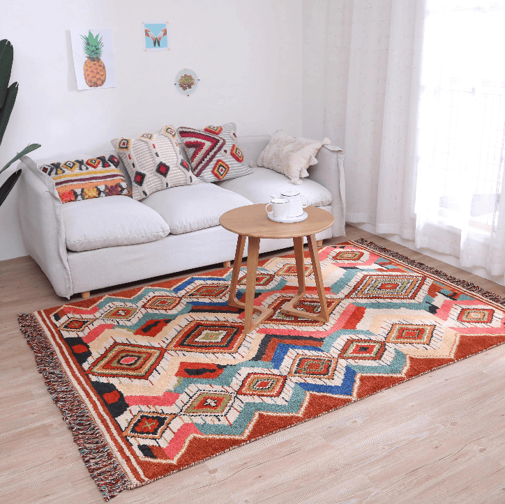 Tapis berbère 160×230 cm multicolore posé devant un canapé blanc, motif géométrique bohème