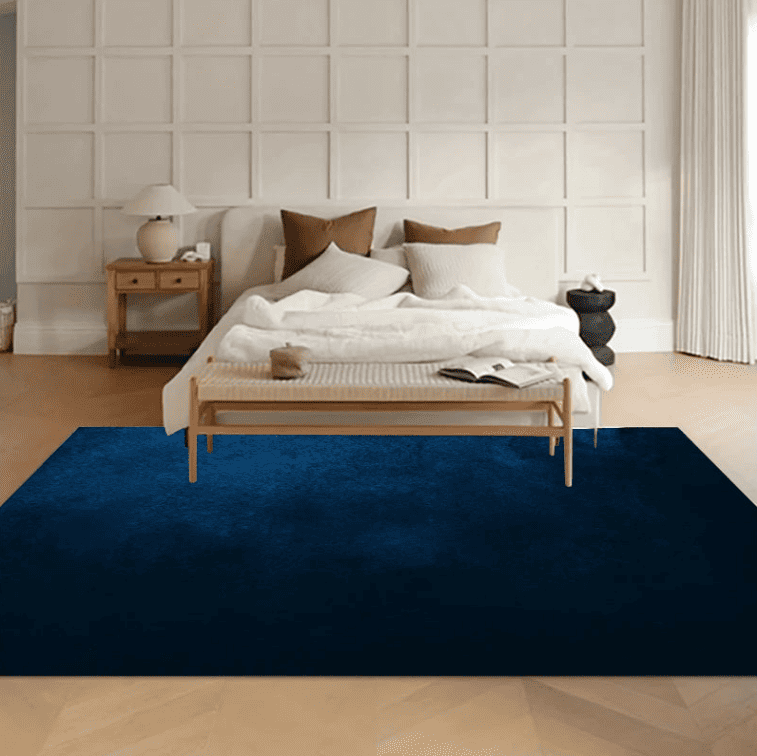 Tapis salon bleu marine doux placé au pied d'un lit dans une chambre élégante et lumineuse.