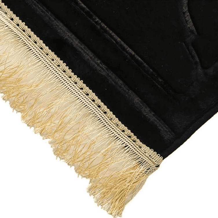 détail des franges dorées et couture d’un tapis de prière noir de qualité