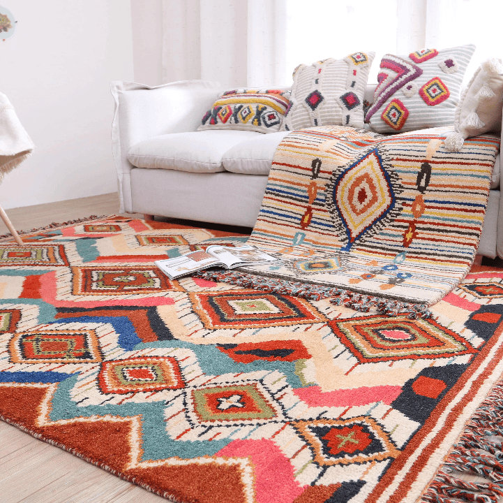 Salon lumineux avec canapé blanc, coussins bohèmes et grand tapis berbère 200×300 cm aux motifs colorés tombant en cascade.