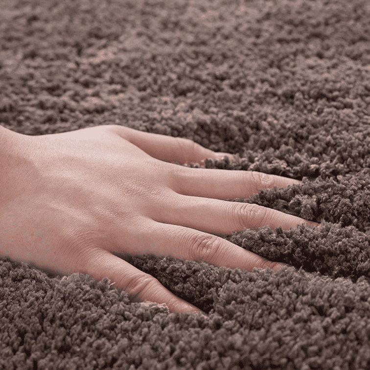 main posée sur un tapis de bain doux en microfibre montrant le confort et la texture