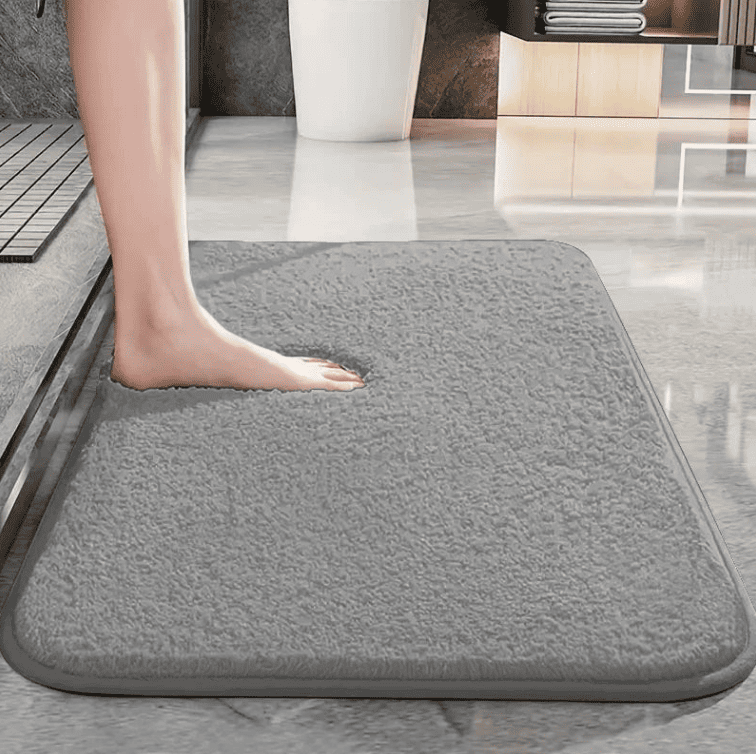 personne posant le pied sur un tapis de bain gris absorbant et antidérapant