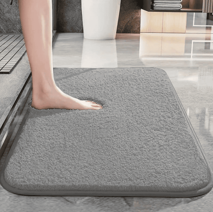 personne posant le pied sur un tapis de bain gris absorbant et antidérapant