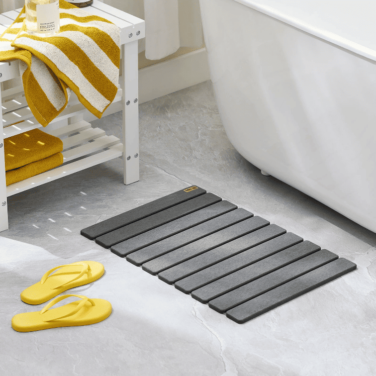 tapis de bain absorbant diatomite gris posé dans une salle de bain moderne près de la baignoire