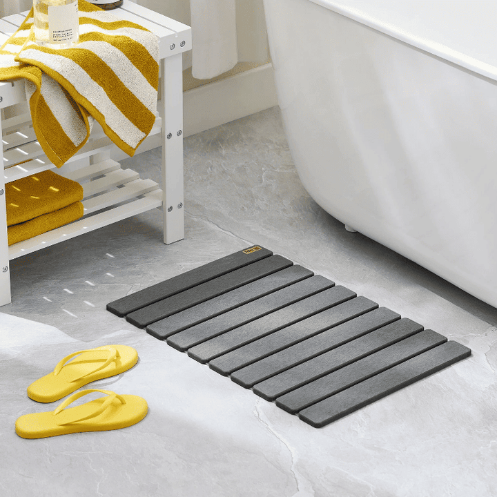 tapis de bain absorbant diatomite gris posé dans une salle de bain moderne près de la baignoire
