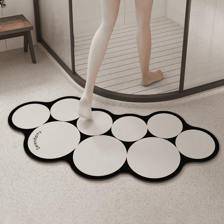 Tapis de bain en diatomite beige à bulles décoratives, absorbant rapidement l’eau sous un pied sortant de la douche.