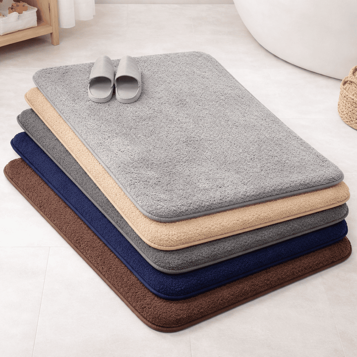 tapis de bain absorbant et antidérapant en plusieurs couleurs empilés dans une salle de bain moderne