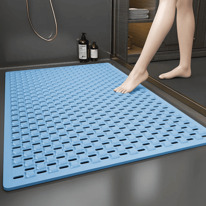Sortie de douche sécurisée pour seniors : tapis de bain antidérapant grand format bleu posé sur le sol, avec drains intégrés pour évacuer l’eau et éviter les glissades.