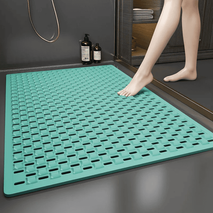 Tapis de bain antidérapant grand format couleur menthe, posé devant la douche pour offrir une surface sécurisée et drainée, idéal pour prévenir les chutes des seniors.