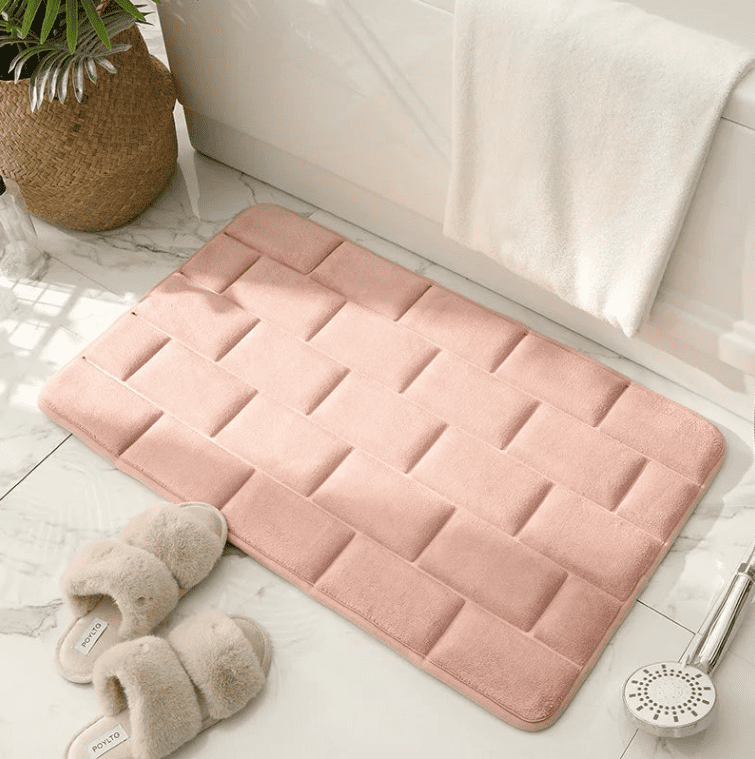 tapis de bain rose moelleux posé au sol avec serviettes, tapis salle de bain absorbant et antidérapant