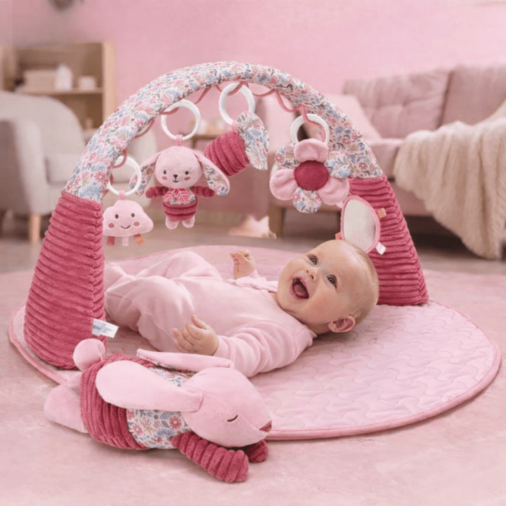 Bébé allongé sur un tapis d’éveil 3 en 1 rose avec arche et jouets suspendus