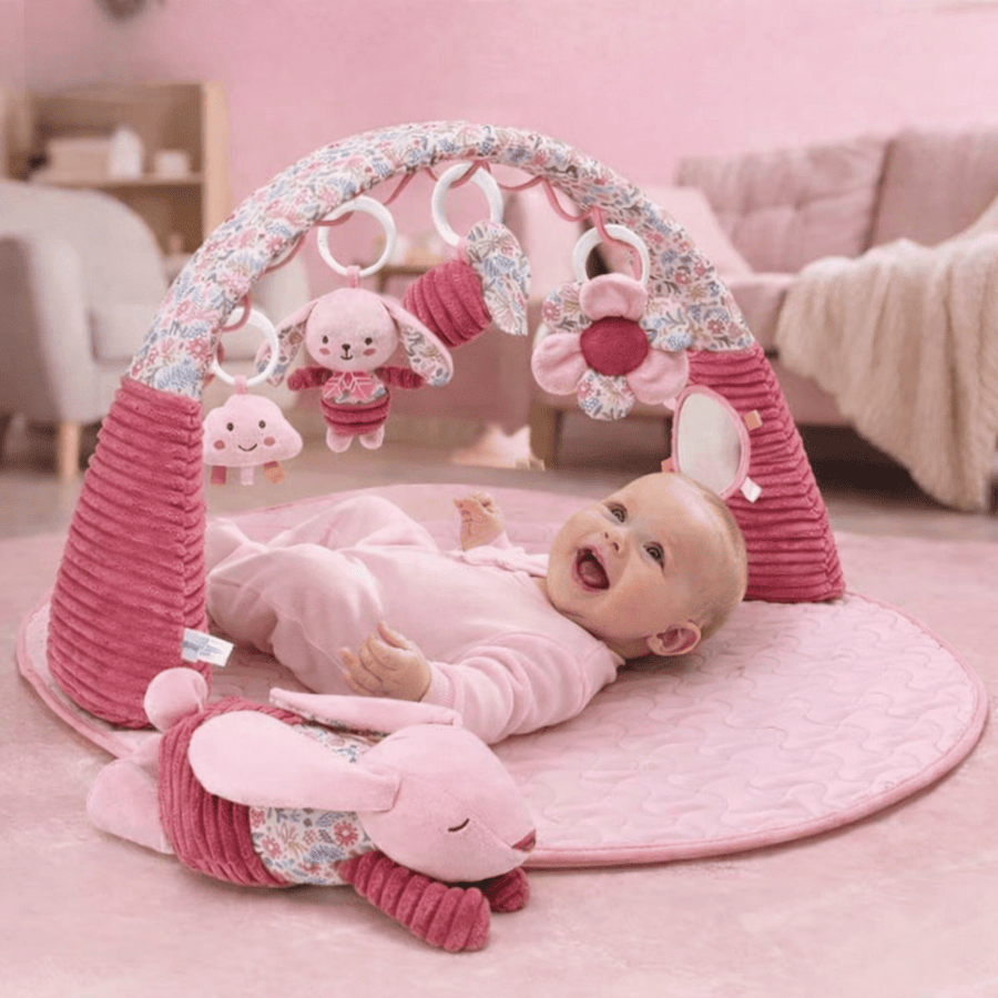 Bébé allongé sur un tapis d’éveil 3 en 1 rose avec arche et jouets suspendus
