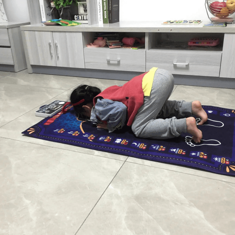 Enfant utilisant un tapis de prière électronique interactif avec guide vocal pour apprendre la prière facilement
