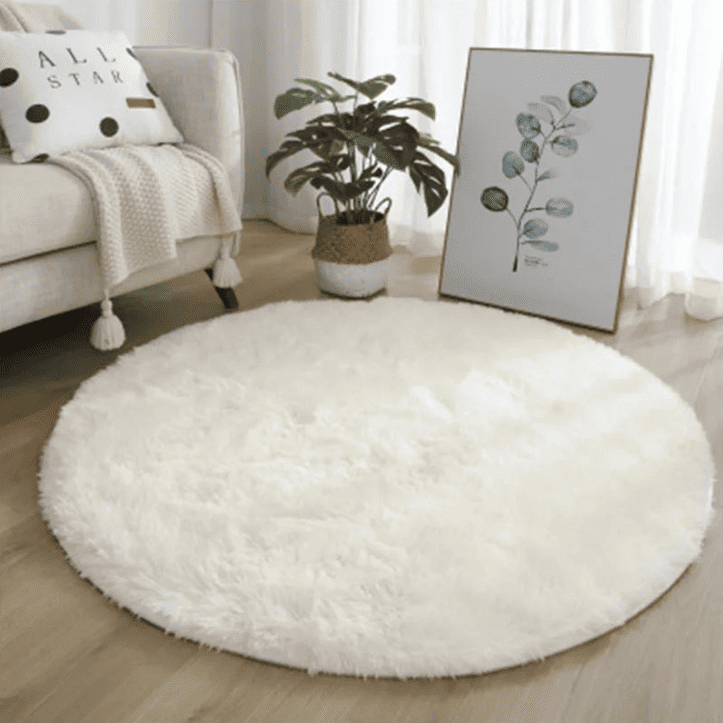 Tapis rond duveteux blanc dans un salon cosy avec décoration végétale et lumière naturelle.