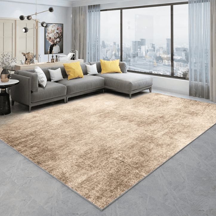 Tapis beige 200×300 cm dans un salon moderne avec canapé gris, coussins jaunes, et grande baie vitrée sur vue urbaine.