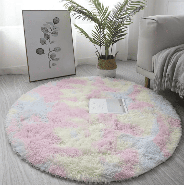Tapis rond multicolore pastel à poils longs, posé dans un salon cosy près d’un canapé et d’un cadre décoratif.