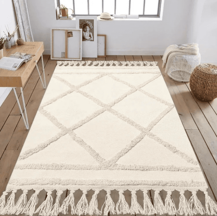 Tapis de salon scandinave crème à motifs losanges en relief avec franges, posé sur un parquet clair dans un intérieur minimaliste et lumineux