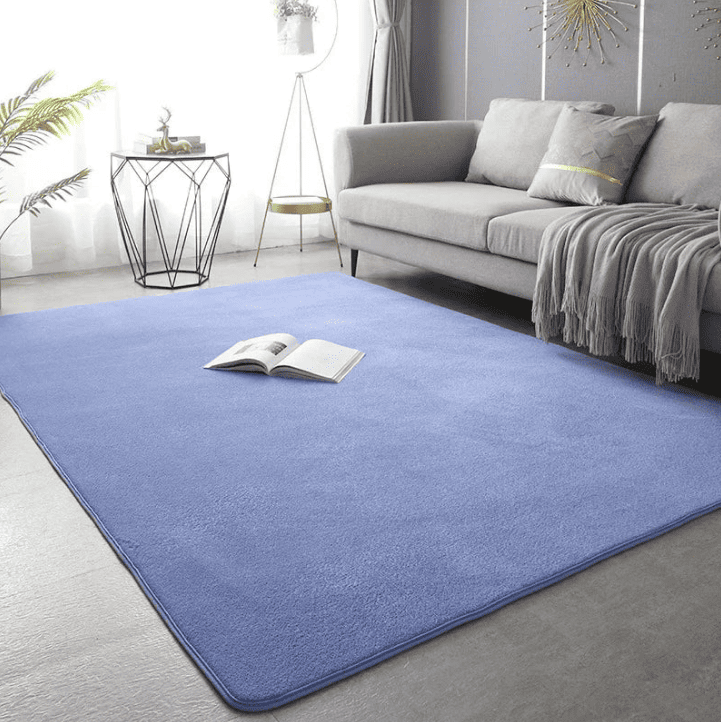 Grand tapis XXL de couleur bleu clair posé dans un salon lumineux avec canapé 