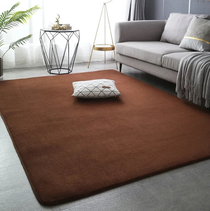 Grand tapis de salon XXL de couleur marron, posé sur un sol clair dans un salon moderne