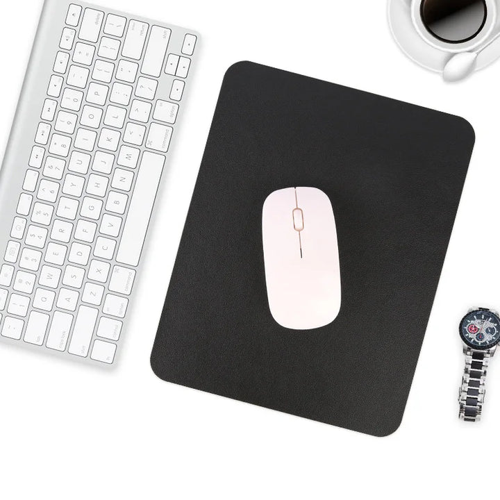 Tapis de souris en cuir noir utilisé sur un bureau avec clavier et souris