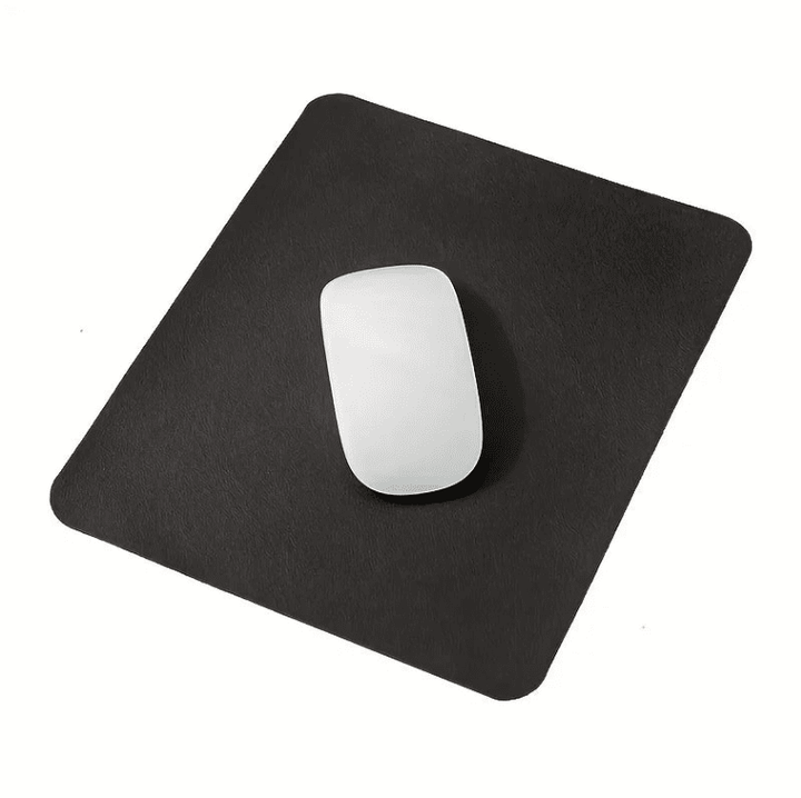 Tapis de souris cuir noir avec souris blanche posé sur un bureau